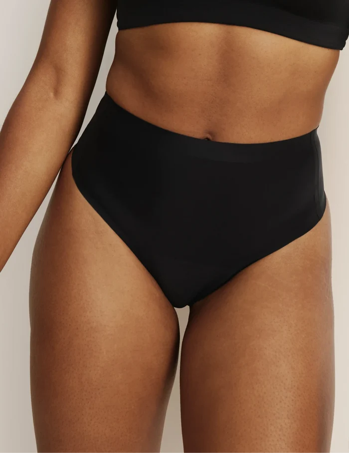 Gin has 38” hips, and wearing KNIX S | Front view of model wearing the Light Leakproof No-Show High Rise Thong highlighting the coverage and smooth fit | Black
