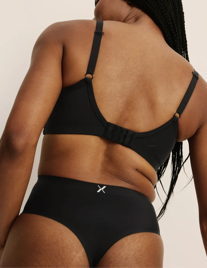 Gin has 38” hips, and wearing KNIX S | Back view of model wearing the Light Leakproof No-Show High Rise Thong highlighting the coverage and smooth fit | Black