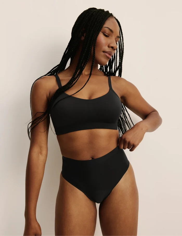 Gin has 38” hips, and wearing KNIX S | Full-body view of model wearing the Light Leakproof No-Show High Rise Thong highlighting the coverage and smooth fit | Black