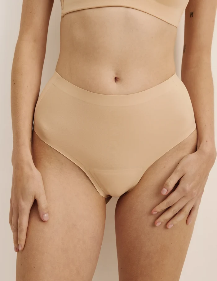 Molly has 35.5” hips, and wearing KNIX S | Front view of model wearing the Light Leakproof No-Show High Rise Thong highlighting the coverage and smooth fit | Warm Sand